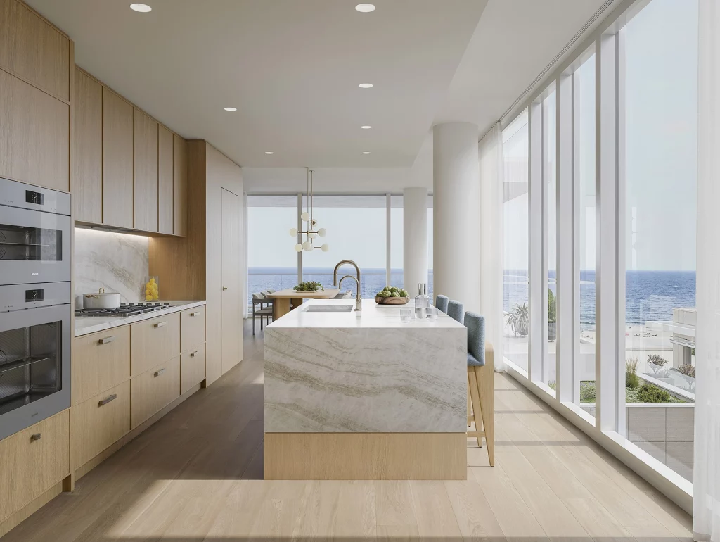 Luxury kitchen in a condo for sale Asbury Park NJ with oak cabinetry, a large stone island, Miele appliances, and floor-to-ceiling windows overlooking the ocean.