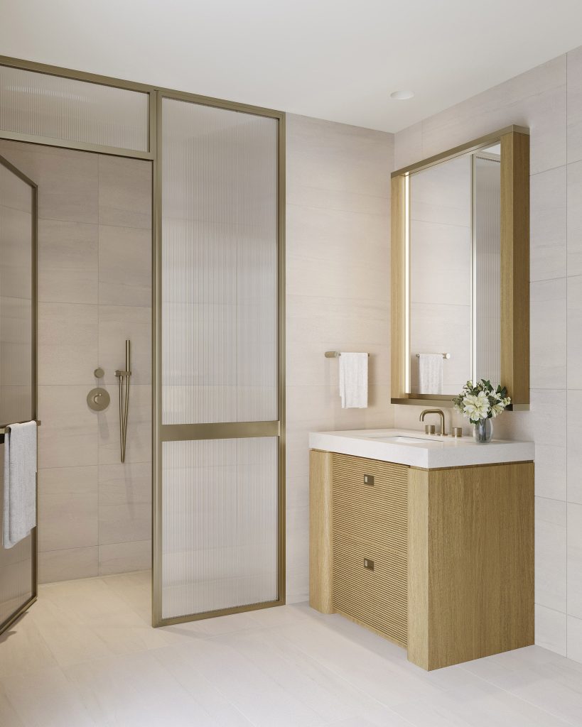 LIDO Asbury Park condos luxury bathroom with a modern wood vanity, illuminated mirror, and a walk-in shower with brass fixtures.